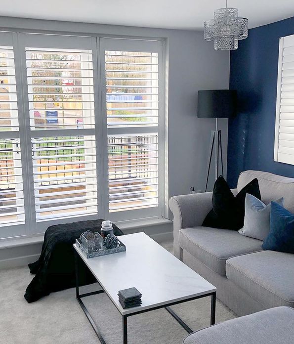 Windows dressed with shutters a living room with grey sofa 