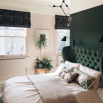 Deep green roman blinds featuring black pattern hanging in a green and white themed bedroom