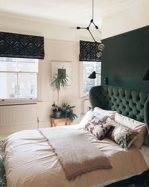 Deep green roman blinds featuring black pattern hanging in a green and white themed bedroom