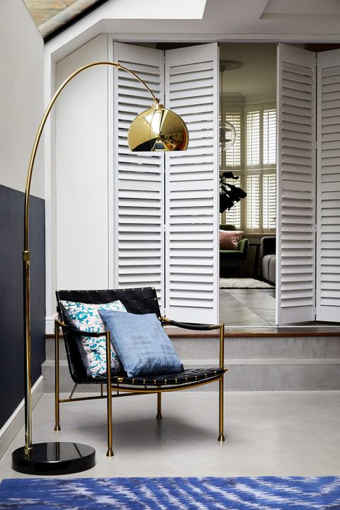 Aura White wooden shutters in living space with large golden lamp
