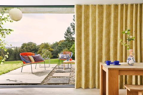 Citrine zebra print curtains hanging on the door of a garden room. Matching citrine and zebra print cushions have been placed in the garden chairs