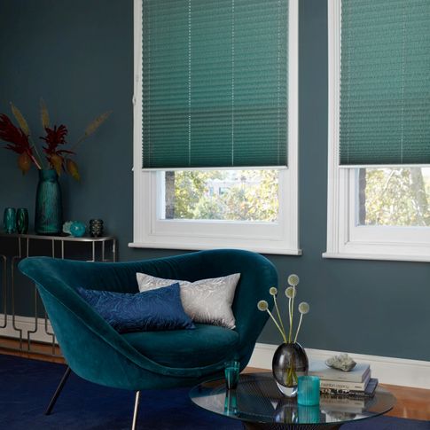 House Beautiful green Pleated blinds dressed on windows in living room. A velvet sofa has been placed near window, with a blue and a silver cushion.