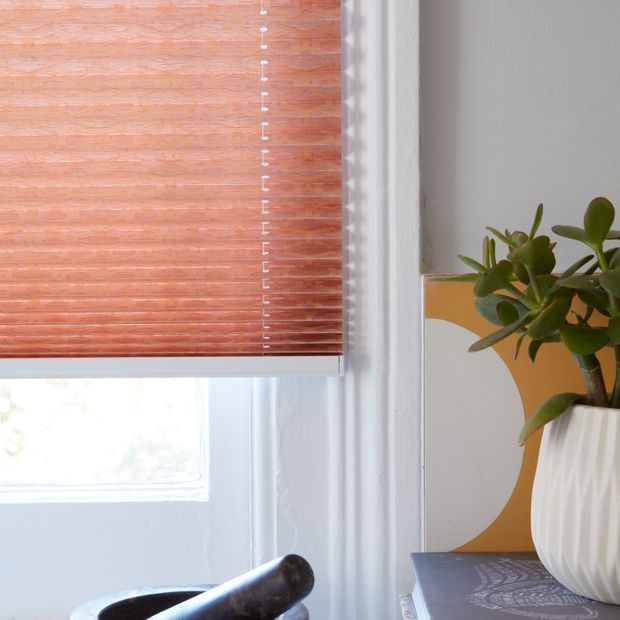 Close up of peach Pleated blinds dressed on the windows of white painted kitchen.