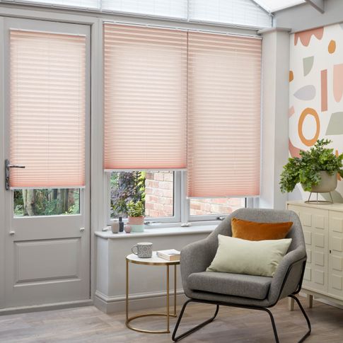 Peachy pink Pleated blinds hanging at varying drop heights on the conservatory doors and windows and upper windows are dressed with white Highgrove pleated blinds.