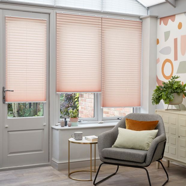 Peachy pink Pleated blinds hanging at varying drop heights on the conservatory doors and windows and upper windows are dressed with white Highgrove pleated blinds.