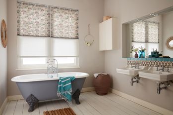Transition Pleated blinds with printed dot-tree pattern and a sheer white blind dressed on windows in the bathroom.  A grey bath is placed in the bathroom.