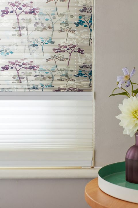 Close up of light grey Transition Pleated binds featuring some trees printed with dots in turquoise or purple on top blind and sheer white blind underneath.