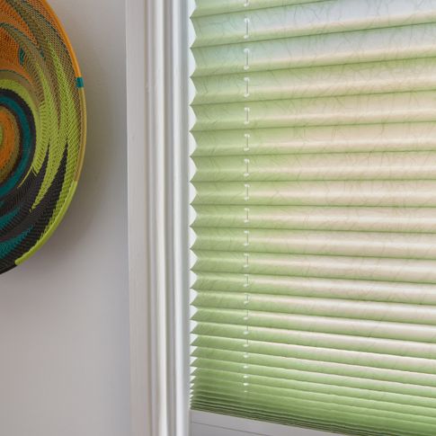 Close up of mint green and white Transition Pleated blinds dressed on the window in dining room.