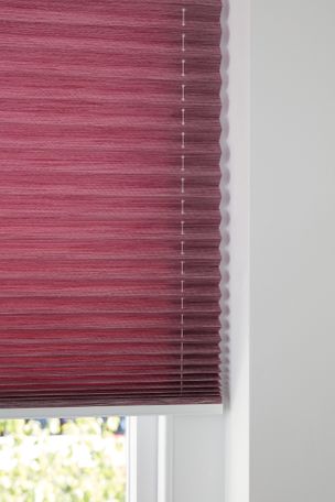 Close up of maroon Pleated blinds dressed on a window.