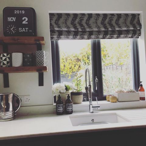 Fade-out black and white wavy line zig-zag printed roman blinds hanging on windows in kitchen