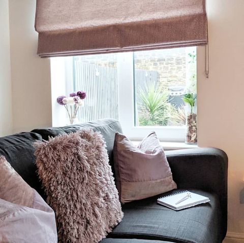Grey sofa with pink cusions and fluffy pink cushion window featuring pink roman blind
