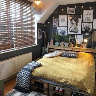 Boys bedroom with yellow bedding, dark walls filled with black and white pictures featuring dark wooden venetian blinds with tape