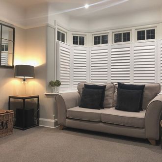 Living room shot, grey sofa, dark grey cushions and window feature white shutters