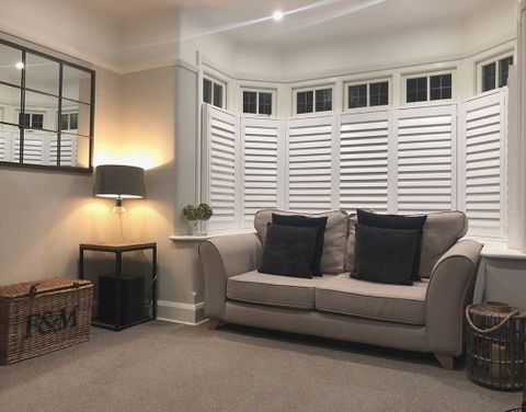 Living room with grey sofa, dark grey cushions and window feature white shutters