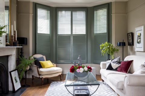 green custom colour full height shutters in living room with cream sofas