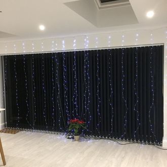 Black vertical blinds decorated with lights dressed on doors of living room