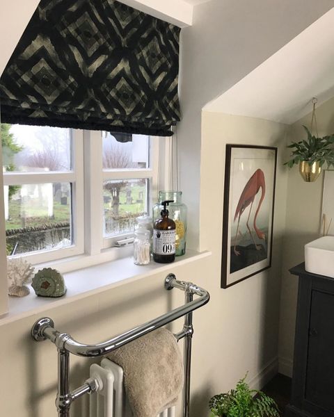 Mint green roman blinds featuring geometric print hanging on windows of bathroom