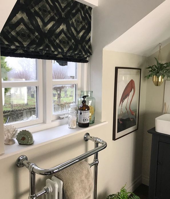 Mint green roman blinds featuring geometric print hanging on windows of bathroom
