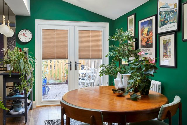brown pleated blinds fitted to door windows in a dining room decorated in green and has potted plants around the room