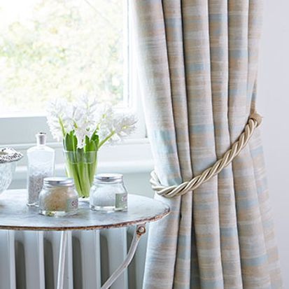 Tied back Riviera Mist curtains by a stone coffee table
