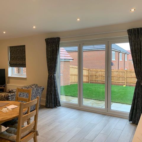 Dark grey print curtans dressed on the patio door and roman blinds drressed on window of lounge