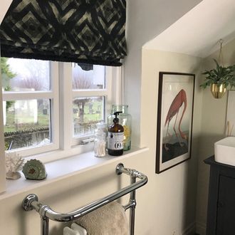 Harkness Gasoline Roman blind with Collette fringing in Kohl in en-suite with flamingo picture and metal towel rail