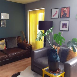 Yellow vertical blinds with guitar, brown leather sofa and black lamp