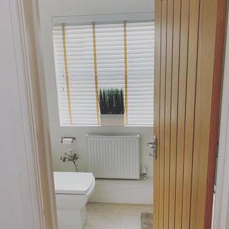 White wooden blinds with tape in small bathroom with wooden door