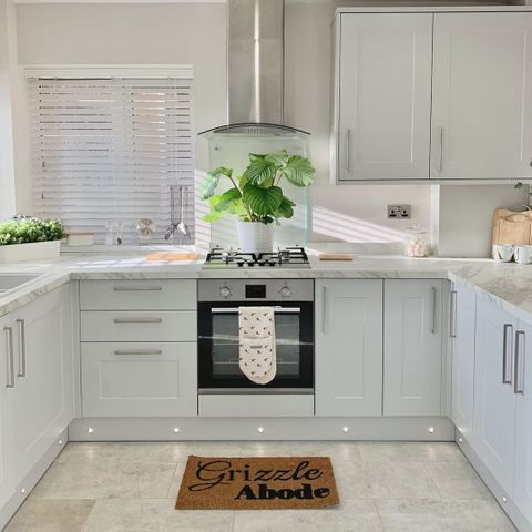White wooden blinds in white kitchen with large plant and DIY doormat