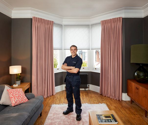 Advisor on pink rug in front of blush pink floor length curtains and white blinds