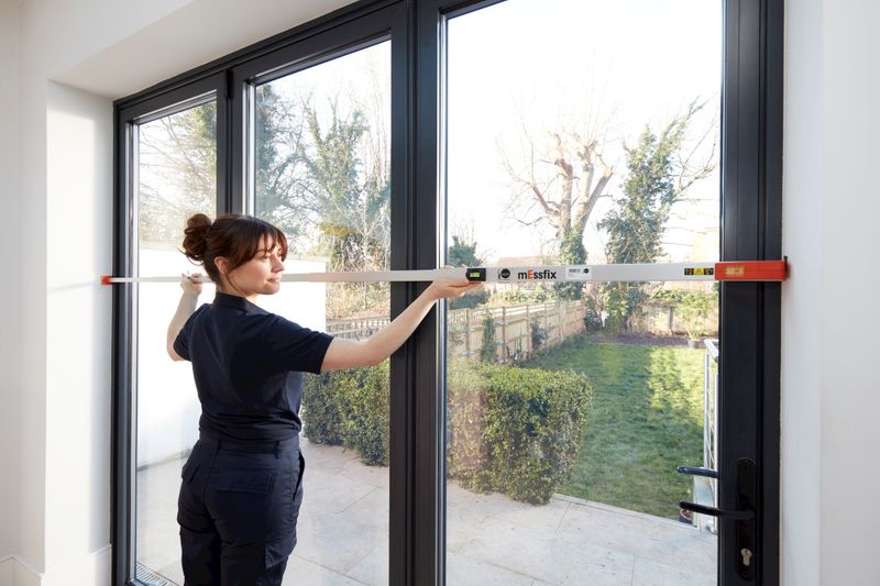 Female advisor measuring long glass windows out to garden