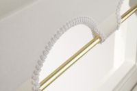 arch shaped hem with a brass coloured pole running through the material of a roller blind