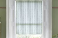 green striped roller blind in white window on a green wall
