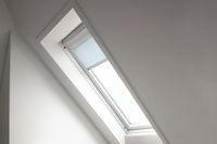 A blue pleated skylight blind fitted to a skylight window that has white decorated walls