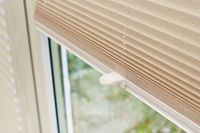 close up of cream pleated blind with a tab on window