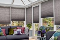dark grey pleated blinds at different heights on conservatory windows behind grey sofas
