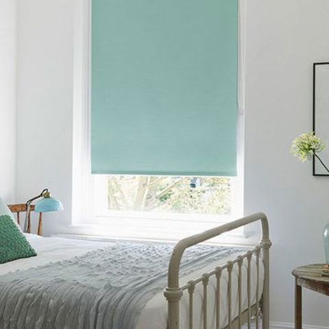 Light blue roller blind fitted to a rectangular window in a bedroom decorated in white