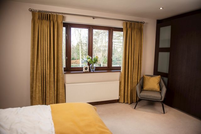 Yellow curtains fitted to a series of short rectangular windows in a bedroom decorated in yellow and neutral colours