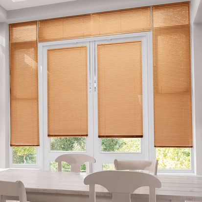 Orange Perfect Fit venetian blinds on dining room french doors. The blinds are finished in the Spectrum Soft Orange style and sit alongside modern dining room furniture including a cream topped dining table, and white dining room chairs.