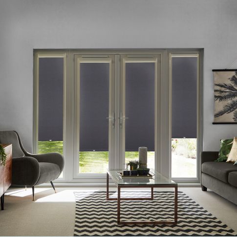 Acacia Black Perfect Fit Roller blinds on four French Doors in a modern living room. The blinds are black and contrast against a sofa, armchair and coffee table.