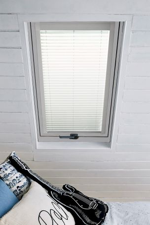 Singular loft window showing white Classic Skylight Venetian blinds. The blind sits on single window, with light blocked fully so it cannot shine into the loft bedroom.