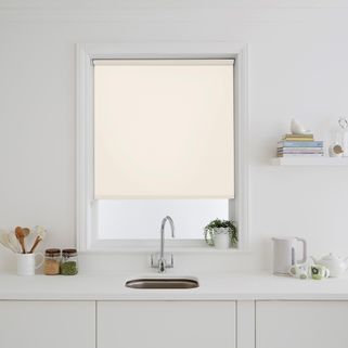 Warm cream Tempest Cream Roller blinds fitted in a simple window in a modernistic kitchen. The blind is behind a sink and almost closed, blocking out the light.