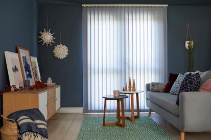 White vertical blinds fitted to tall window in a blue decorated living room