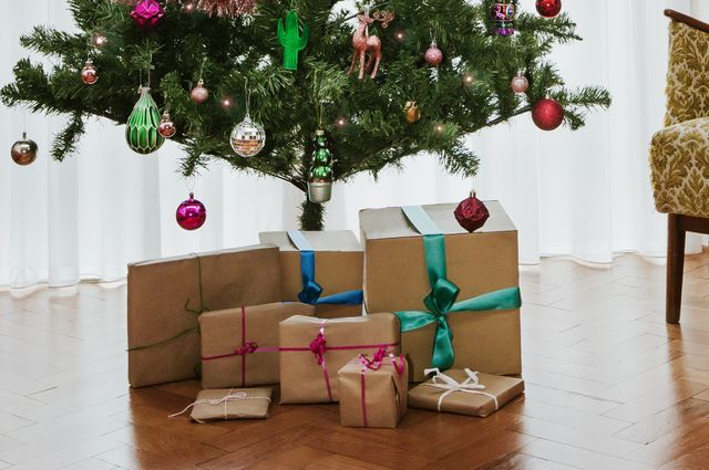Presents under a Christmas tree wrapped in brown paper and multi coloured ribbons
