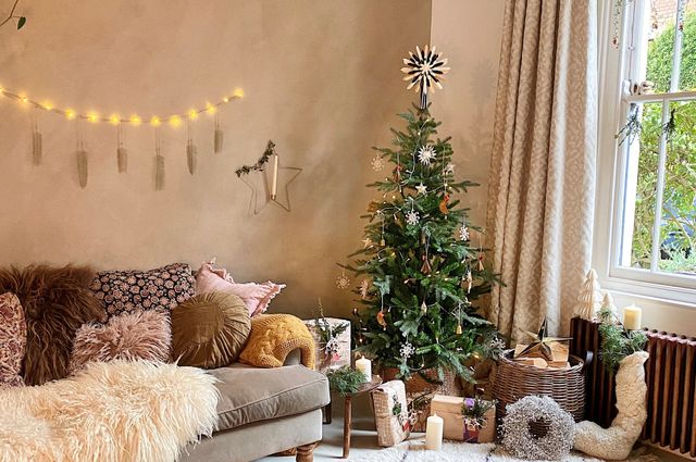 Neutral living room with Christmas tree decorated in the corner, natural textures in the rug and foliage decorations