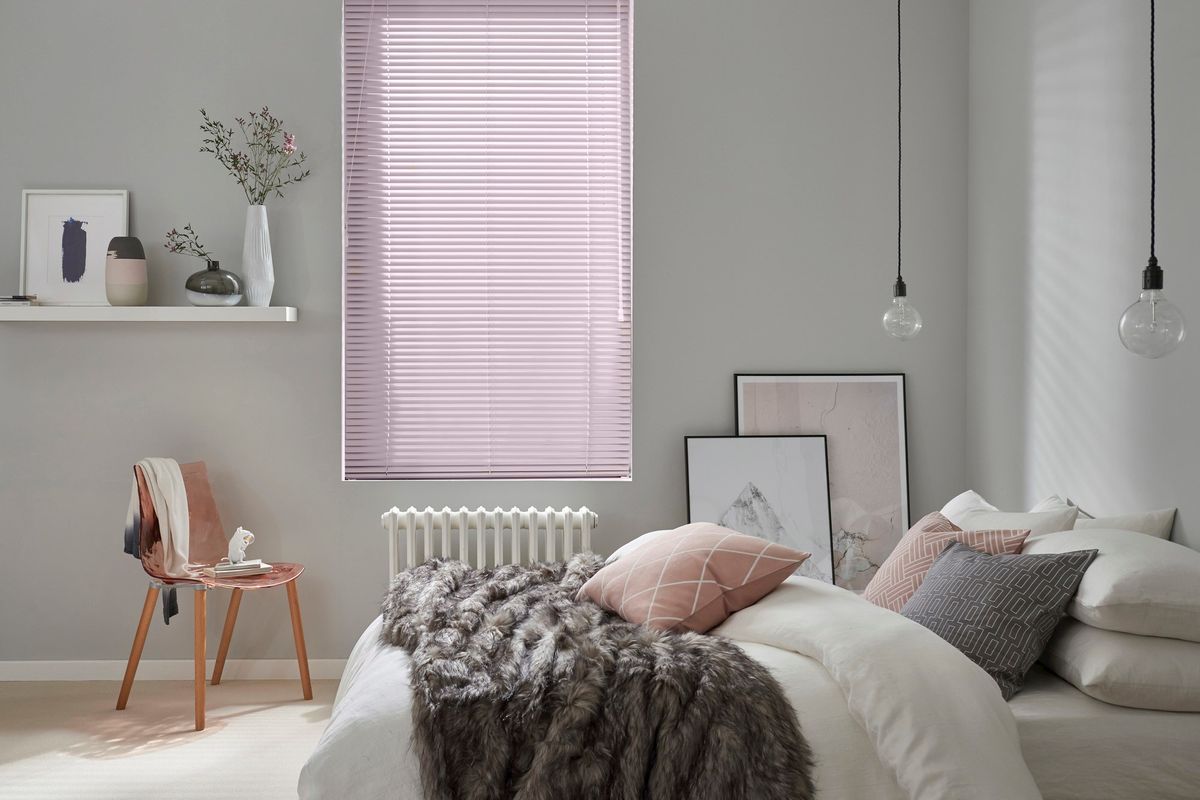 Sugar pink metal venetian blind in bedroom window with white and pink accessories