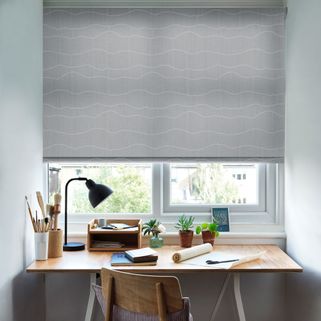 The Atlas Marine Roller blind hangs freely in a home office. The printed product hangs above a desk and provides privacy.
