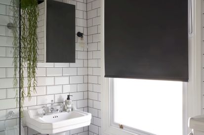 White-tile bathroom with a black blind and monochrome accents