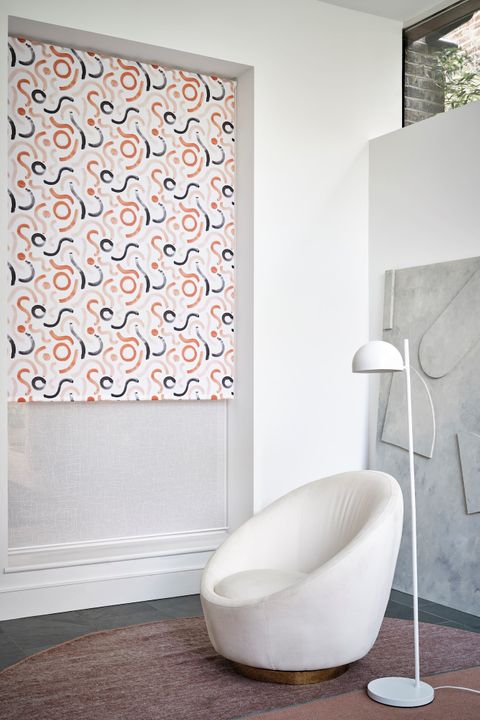 A relaxed grey and white space, with a white, light pink, orange and blue patterned blind