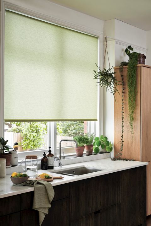 marble and wood kitchen with a light green blind and hanging plants